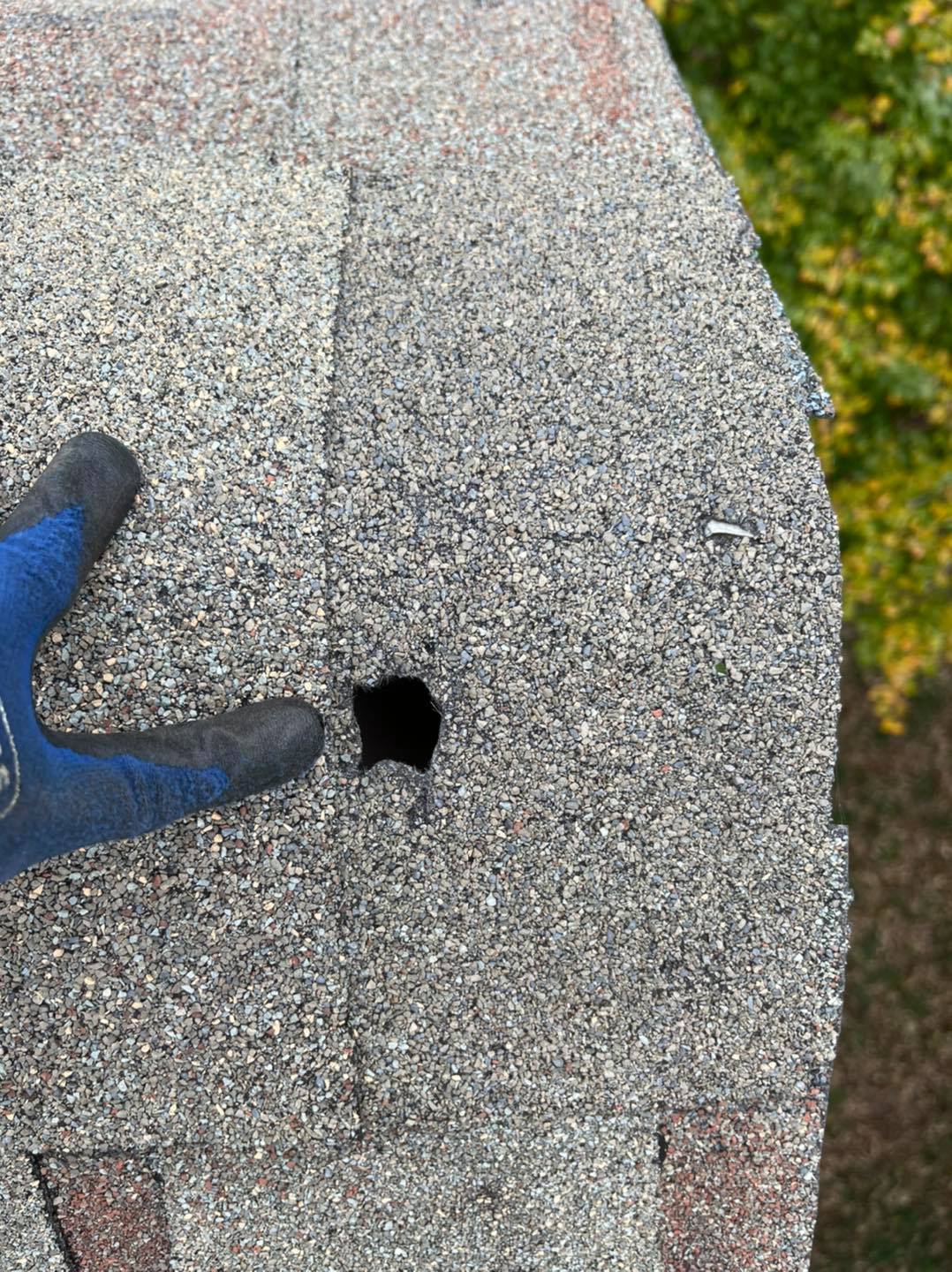 An example of a hole in the shingles on a client's roof caused by storm damage